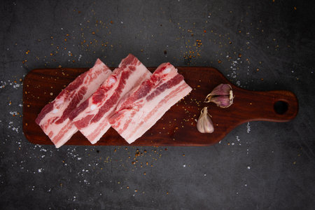 Raw pork ribs on wooden cutting board, black background, top viewの写真素材