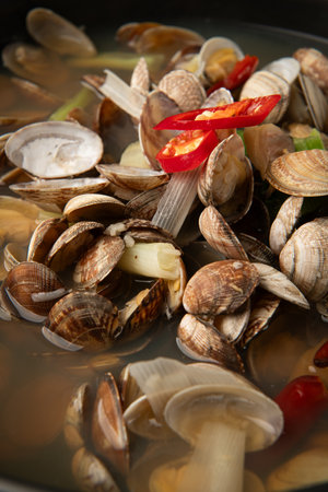Cooked clams with chili pepper in pot, closeup. Seafood soup