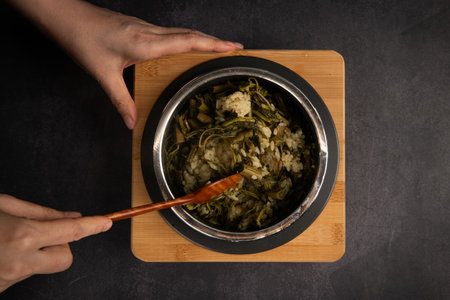 Woman eating cabbage and rice in a pot on a black backgroundの写真素材
