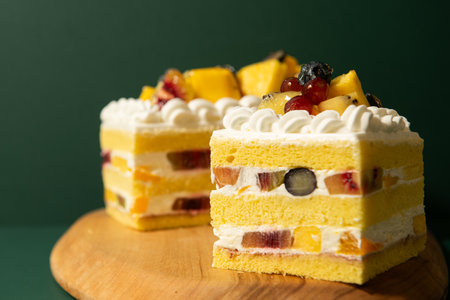 Piece of cake with fruits on a wooden board on a green background