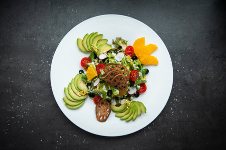 Delicious avocado and tomato salad with orange slices on a white plate