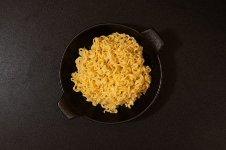 Instant noodles in a black bowl on a black background, top viewの写真素材