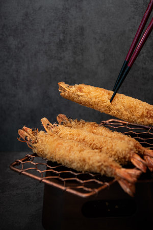 Deep fried prawns with chopsticks on black background, copy space