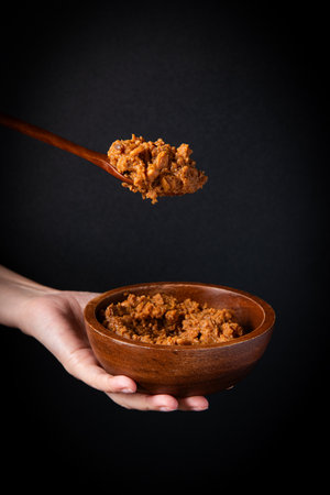 Spoon of curry paste in a wooden bowl on a black backgroundの写真素材