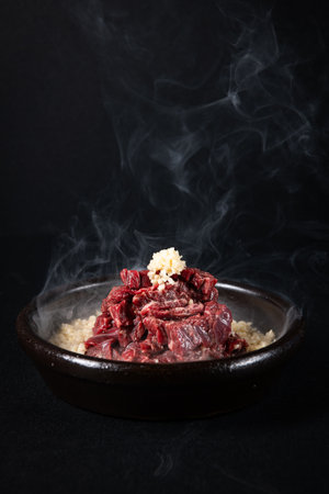 beef steak in a clay bowl on a black backgroundの写真素材
