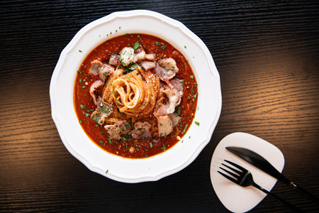 Spaghetti Bolognese with bacon and herbs on wooden table