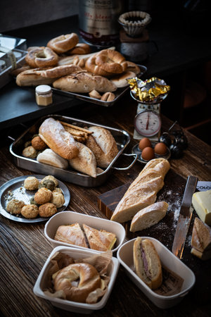 Variety of bread and croissants on old wooden table.