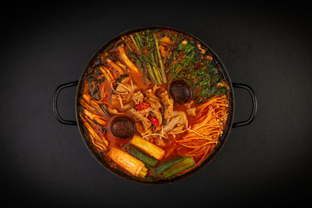 Hot pot with vegetables and meat on black background, top view