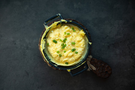 Scrambled eggs in a metal pot on a dark background.