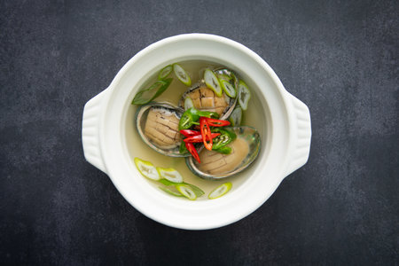 Steamed clam with chili and herbs in white bowl on black backgroundの写真素材