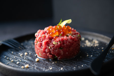 Beef tartare with red caviar on a black plate.の写真素材