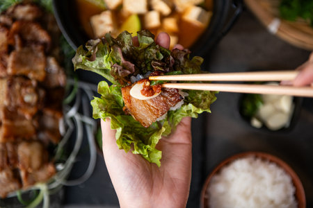 Hands holding japanese food with chopsticks over wooden tableの写真素材