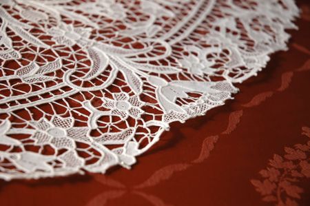 Lace Doily on red tableclothの写真素材