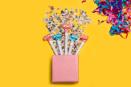 A pink gift box with confetti on a yellow backgroundの写真素材