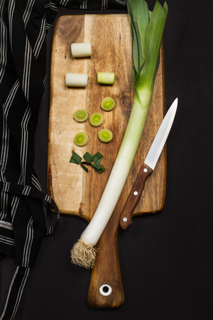 A leek and pieces of it on a wooden boardの写真素材