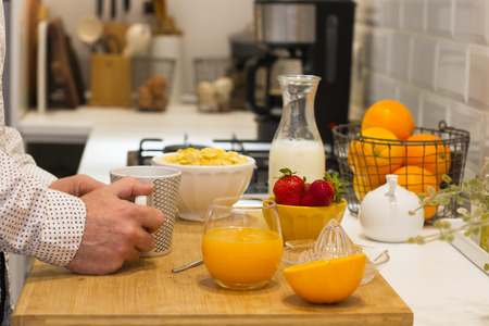 Man having a natural breakfast on a wooden table in the kitchenの写真素材