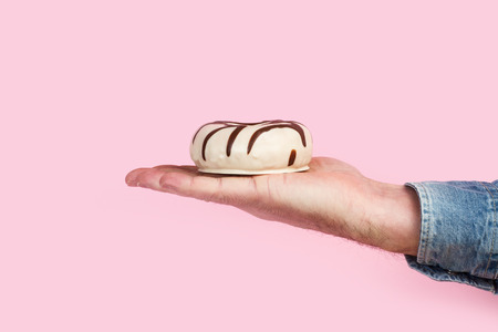 Man with a donut on his hand in a pink backgroundの写真素材