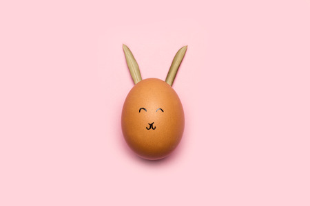 An egg with face and rabbit ears on a pink backgroundの写真素材