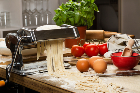 pasta machine with noodles and ingredients on a wooden tableの写真素材
