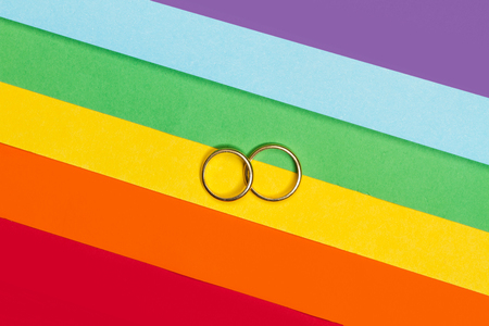 Two gold rings on a gay pride flagの写真素材