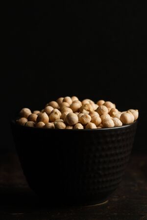 Chickpeas in a black ceramic bowl on a darl backgroundの写真素材