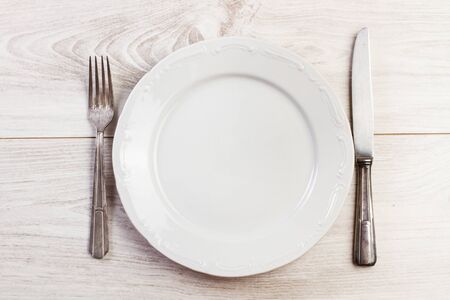Silver cutlery and a plate on a wooden table
