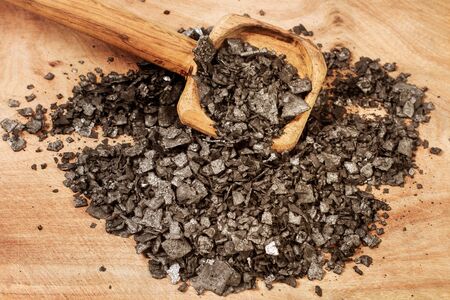 Black salt in flakes on a wooden spoonの写真素材