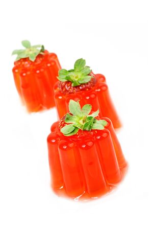 Three strawberry jellies with green leaves on a white backgroundの写真素材