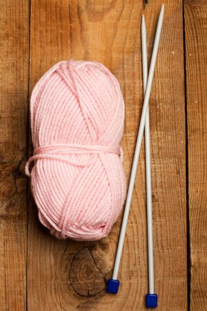Pink wool ball and needles on a wooden tableの写真素材