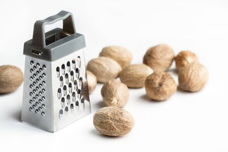 A little grater with nutmegs on a white background