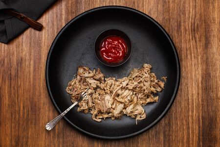 Pulled pork in a black plate on a wooden tableの写真素材