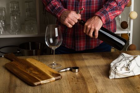 Man opening a glass of red wine on a wooden table