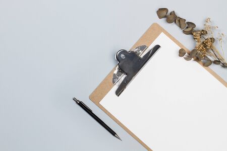 A clipboard table with paper and a pencil on a gray backgroundの写真素材