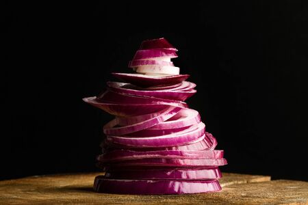 A heap of sliced purple onion on a wooden table on a dark backgroundの写真素材