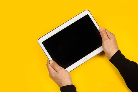 Man holding a tablet in his hands on a yellow background