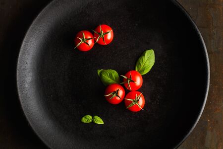 Red cherry tomatoes on a black plateの写真素材