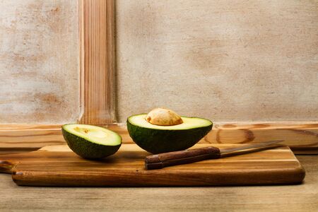 Halved avocado on a wooden kitchen board