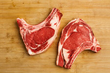 Two raw veal steaks on a wooden kitchen board