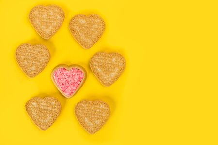 Heart shape cookies on a yellow background in a top view
