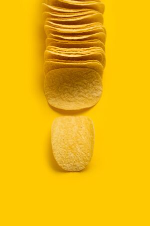 A lot of potatoes chips in line on a yellow backgroundの写真素材