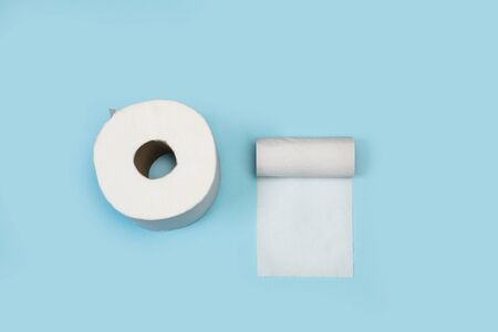 A toilet paper roll and other almost empty on a light blue backgroundの写真素材