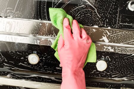 Man with rubber gloves cleaning oven and microwave door