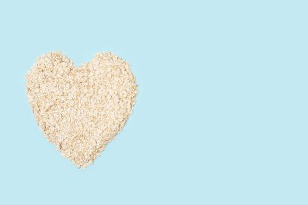 A heart shape of oat flakes on a light blue background in a top view