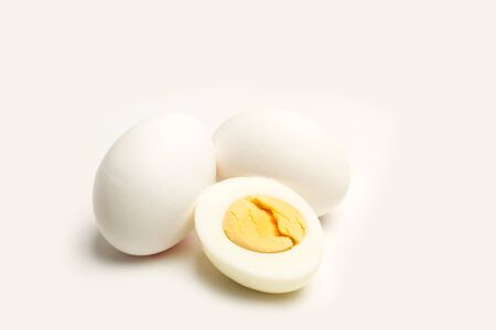 Halved boiled egg and two eggs on a white backgroundの写真素材