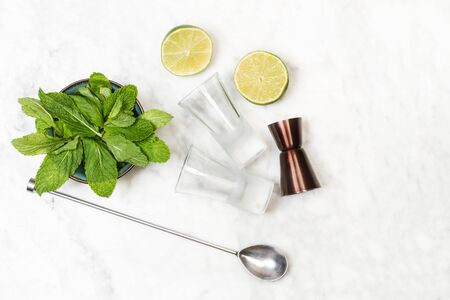 Some ingredients to make a mojito and bartender stuffes on a marble table