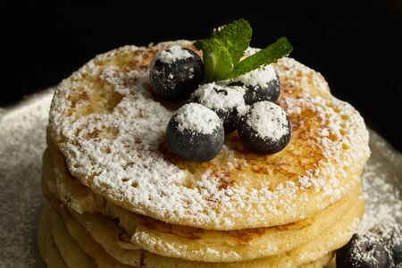 Pancakes with blueberries and icing sugar on an old aluminum pan on a dark backgroundの写真素材