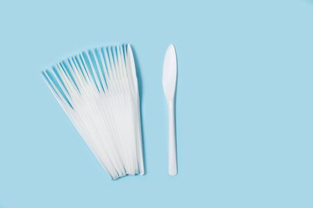 Disposable white plastic knifes on a light blue backgroundの写真素材