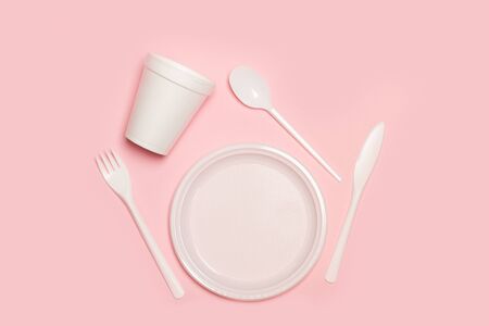 Disposable plastic white tableware set on a pink background in a top viewの写真素材