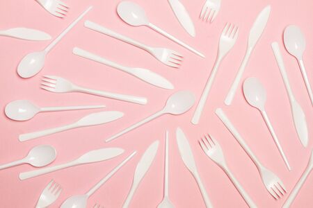 Disposable white plastic flatware on a pink background in a top viewの写真素材