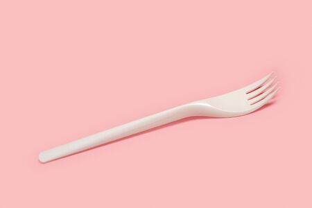Disposable white plastic fork on a pink background in a top viewの写真素材